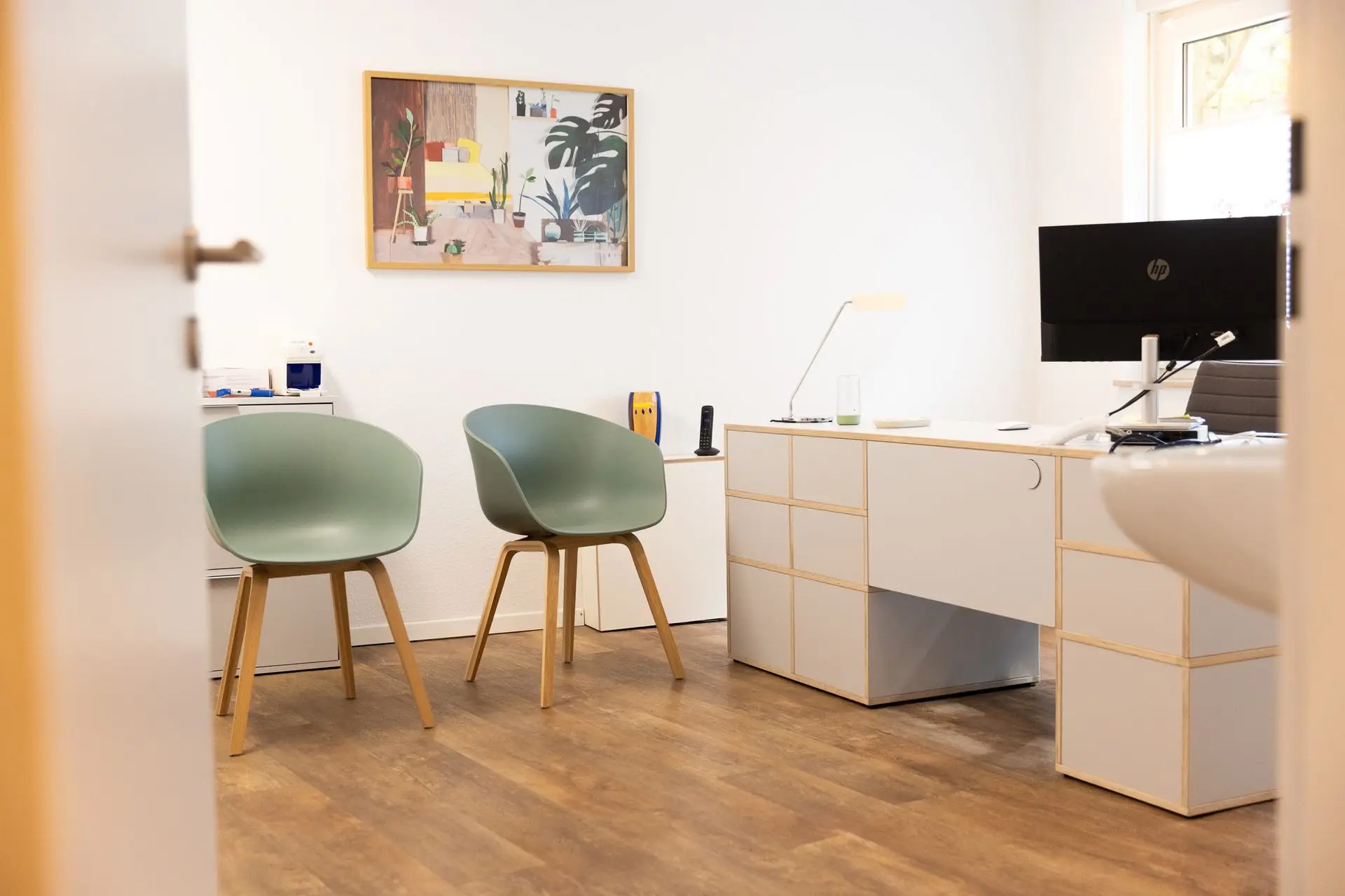 Sprechzimmer der Praxis mit zwei grünen Stühlen